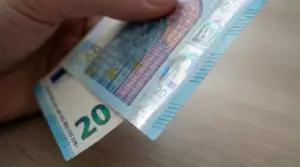 Dettaglio di una banconota da 20 euro tenuta tra le dita, messa in controluce