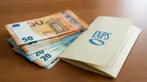 Banconote in euro accanto a una busta con logo INPS su un tavolo di legno