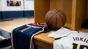 Pallone da basket, lavagna tattica e maglie Washington e Jokic su una panchina in spogliatoio